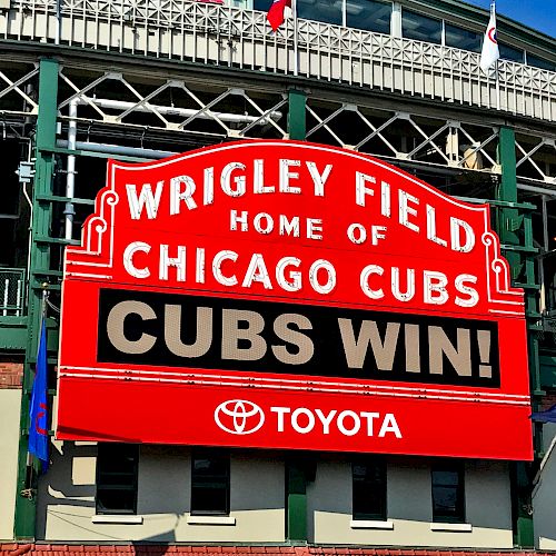 The image shows the iconic Wrigley Field sign, stating "Wrigley Field Home of Chicago Cubs CUBS WIN!" with a Toyota logo at the bottom.