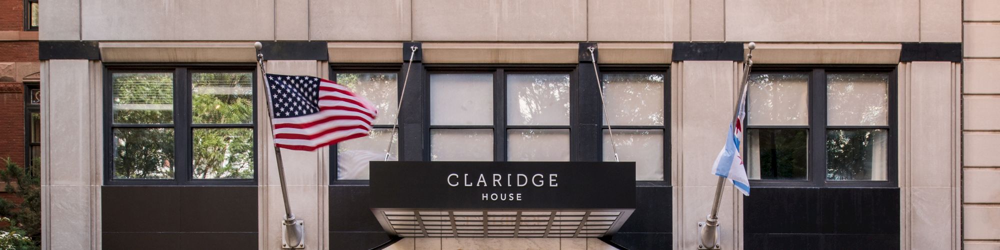 The image shows the entrance of a building named "Claridge House" with outdoor seating and two flags, one American and the other unidentified, displayed.