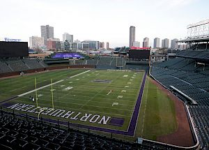 Wrigley Field Stadium with football field markings, empty seats, city skyline in background.