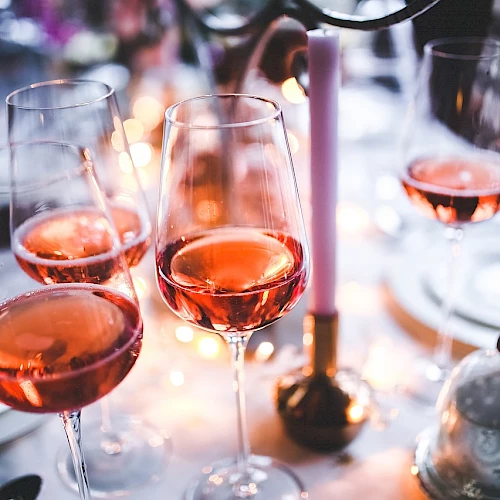 Glasses of ros&eacute; wine on a festive table setting with warm lighting.