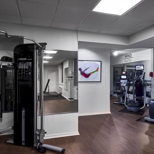 A busy office or classroom with desks, chairs, whiteboards, and several people; a modern workspace with plants and glass partitions.