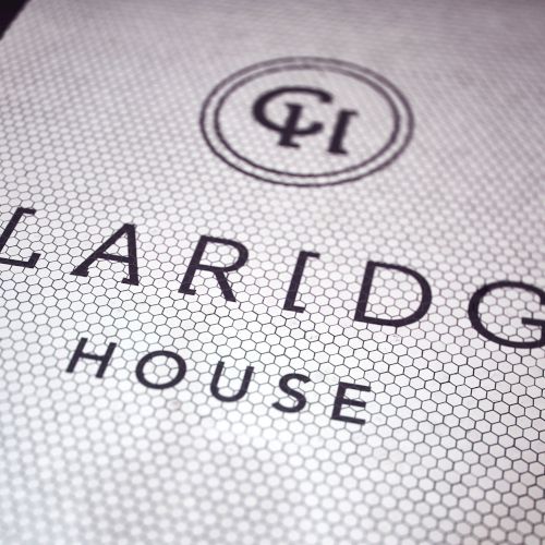 A close-up of a textured label reading &ldquo;CLAIBOURGE HOUSE&rdquo; with a small circular emblem above, on a light fabric or paper surface.