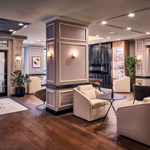 A cozy, modern living room with a gray sofa, wooden coffee table, warm lighting, and earthy decor near a hallway.