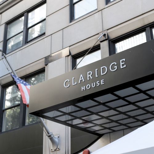 A storefront with a sign that reads &ldquo;L&rsquo;ORAGE&rdquo; or similar, gray brick facade, large windows, and a white awning at street level.