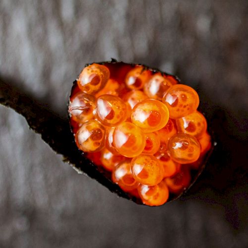 A small glowing cluster of orange-red embers or a spark-like flame with dark surroundings, ending in a bright, heart-like glow.